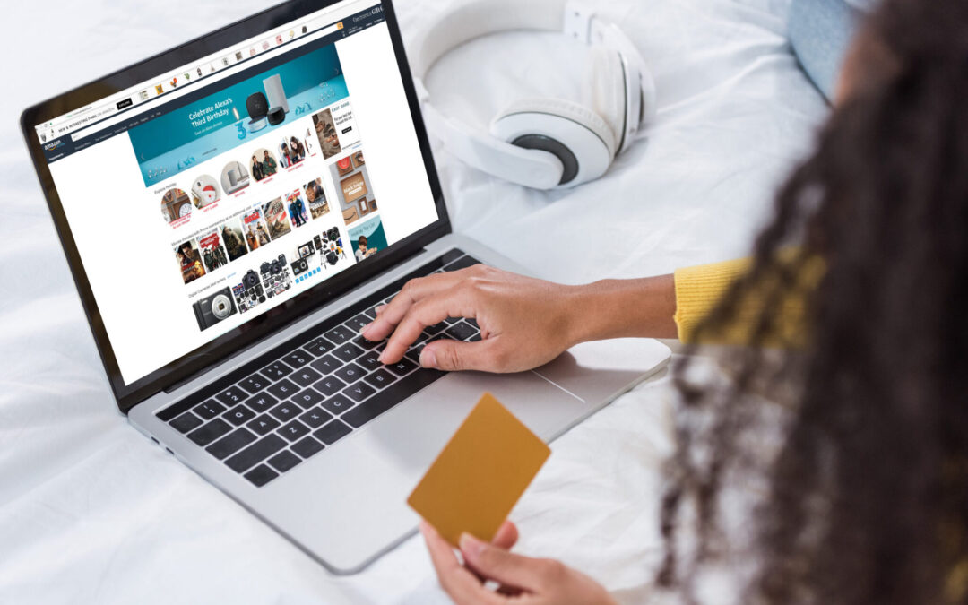 cropped image of woman holding credit card and using laptop with amazon on screen